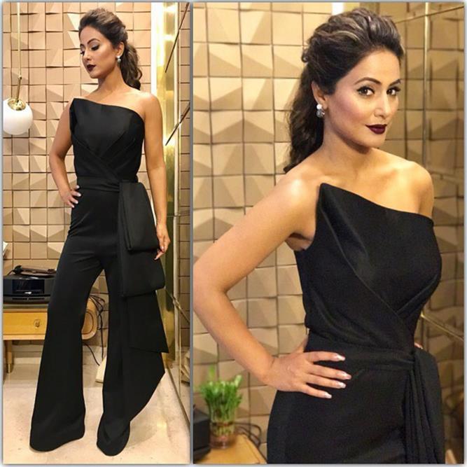 Hina Khan is seen wearing a black jumpsuit and her brownish hair ponytail with dark brown lips.