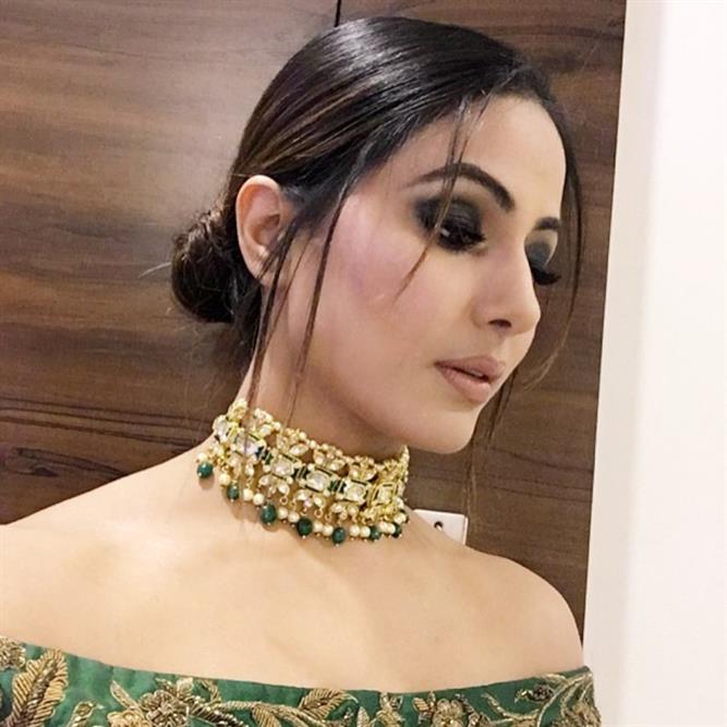 Hina Khan is sporting a stylish messy bun with strands of hair and her black eye makeup just completes the look.